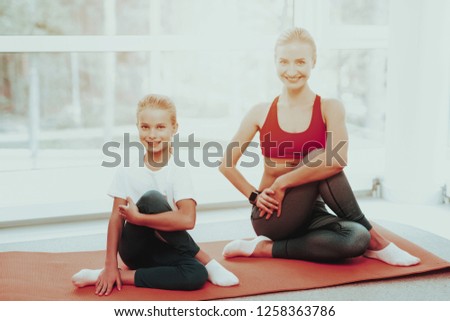 Mother And Daughter Sitting On Gym Carpet. Yoga Concept. Meditation Pose. Active Lifestyle. Camera Staring. Fitness At Home. Holiday Leisure. Body Balance. Sport Exercise. Sunny Morning.