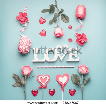 Word love with roses, hearts and decoration ribbons on pastel blue background, top view. Valentines day or abstract love concept