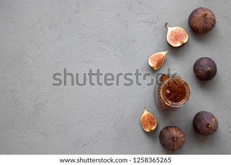 Fig jam in glass jar and fresh figs on concrete background, top view. Flat lay, from above, overhead. Copy space.