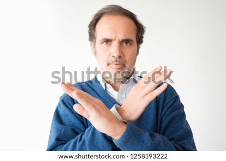 Serious mature man gesturing forbidden with two hands. Handsome middle aged man making stop gesture. Isolated on white. Prohibition concept
