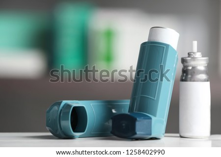 Asthma inhalers on table against blurred background. Space for text Royalty-Free Stock Photo #1258402990