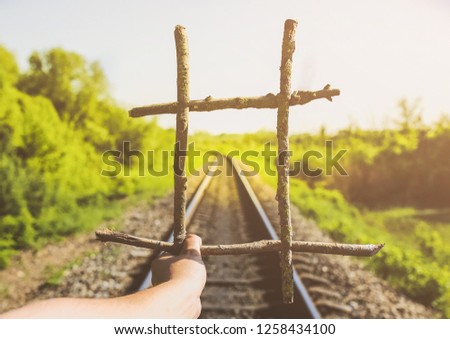 Guy is holding prisons grate made from wooden sticks. Freedom concept photo with rail tracks in the green field. Railway transport industry. Empty road on summer day. Travel lifestyle motivation.