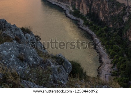 soft focus narrow sea bay aerial photography from above with with rocky stones on foreground and water between mountains on background in twilight darkness evening environment 