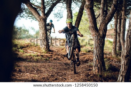 Two riders on mountain bike going down trails in the forest