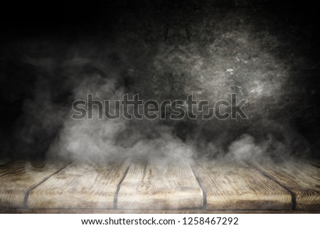 Table background of free space for your decoration and black wall with smoke. 