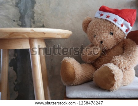 Teddy bear wearing Santa red christmas hat sitting at the coffee table in a cafe