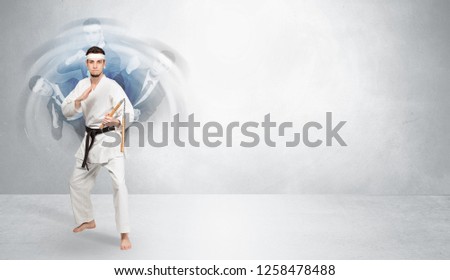Young businessman in suit fighting with empty wall background