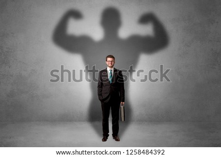 Lovely serious businessman standing with a muscular powerful shadow behind his back