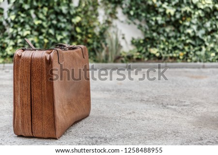 Nice vintage brown suitcase located on the floor of a patio