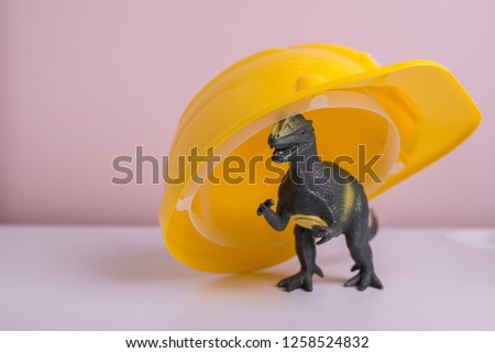 Toy dinosaur at yellow helmet