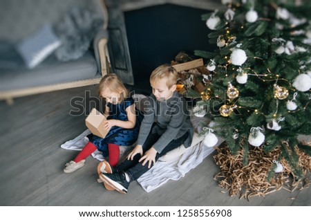children - a boy and a girl are sitting by the fireplace, a New Year tree, playing with cardboard houses, a cozy Christmas decor and children's emotions