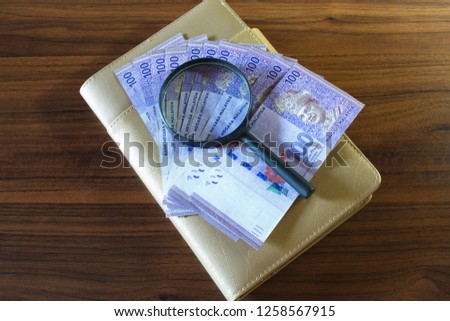 Business concept: Malaysian currency notes, pen, magnifying glass and organizer on table