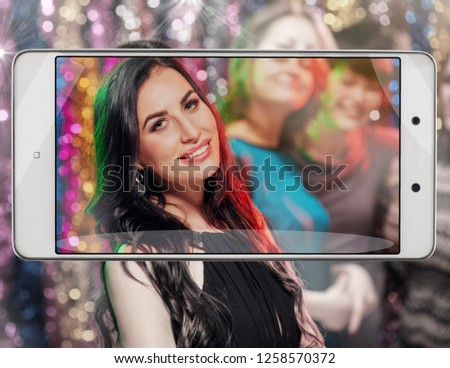 Young happy woman enjoying nightlife and dancing, conceptual image with a smartphone