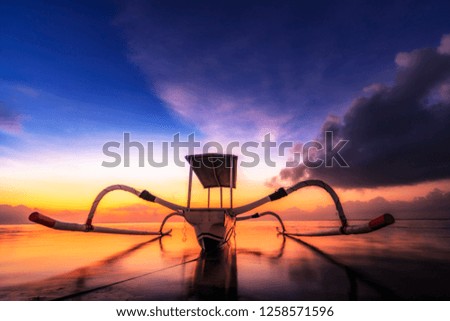 classic old fishing boat from Bali Indonesia. it's called Jukung and swims on the beach in the calm waters in a great sunrise. taken from low position
