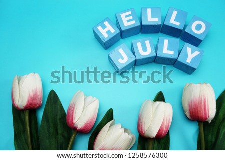 hello july with artificial pink tulip flower on blue background