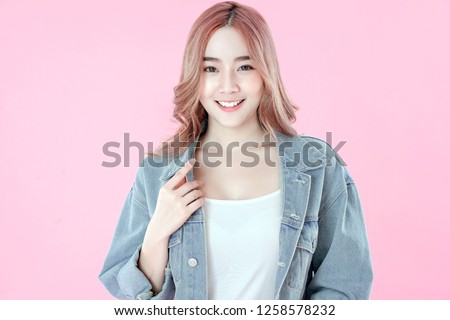 Asian woman smiling with blue jean clothing, pink background