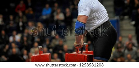  muscular sportsman doing farmer's walk exercise during his competition workout. Strongman sport Royalty-Free Stock Photo #1258581208