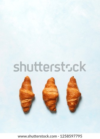 Top view of fresh french croissants on pastel blue background