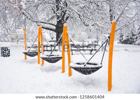 Three nest swings for kids coverd with snow in playground