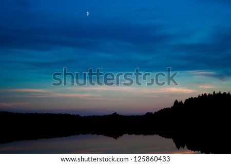 the moon in the late evening sky over the lake Royalty-Free Stock Photo #125860433