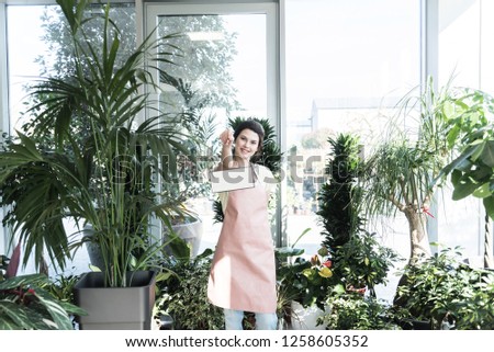 Young smiling woman professional gardener holding the banner with empty copy space in botanical garden center, Gardening service and business concept