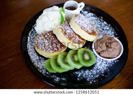 Soft sweet pancakes with cream and kiwi fruits. Sweet breakfast on wooden table. 
