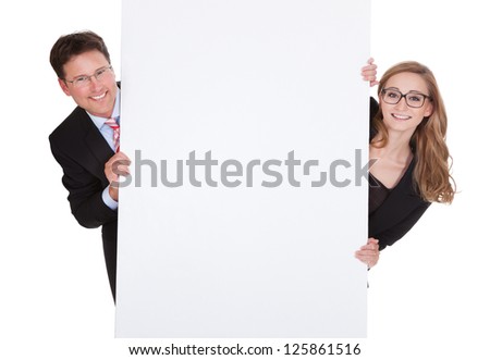 Smiling professional man and woman wearing glasses holding up a blank white sign for your text or advertisement isolated on white