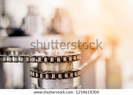 Technology chain drive element of braiding machine. Tinted image. Single strand roller chain going around sprockets on industrial machine in factory. Vintage machinery powered by chain gear.
