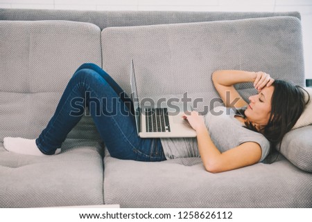 The wife spends time with a laptop sitting on the couch