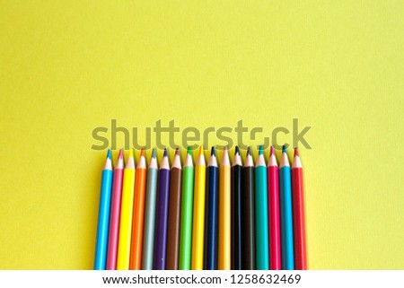 Colored pencils are laid out in a row on a green background, there is a place for the inscription. The concept of drawing or items for the school.