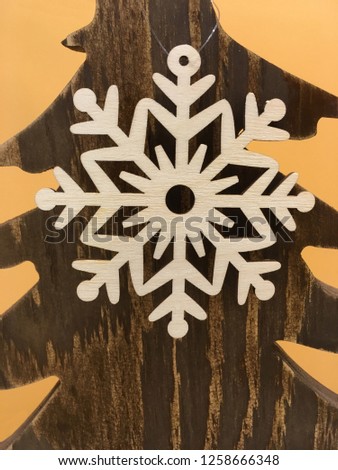 Large white snowflake on the background of a wooden texture with the contours of Christmas trees.