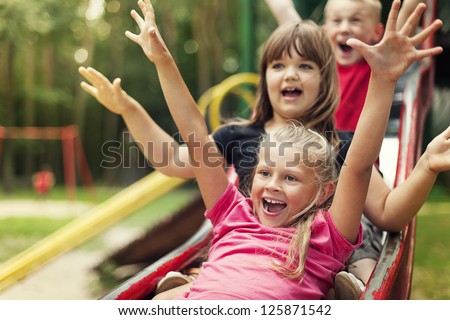 Happy kids playing on slide Royalty-Free Stock Photo #125871542