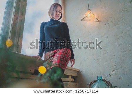 
The girl sits on the window, the student looks thoughtfully. Model posing at the window. Concept: romance and longing
