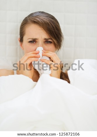 Ill woman with hanky laying in bed