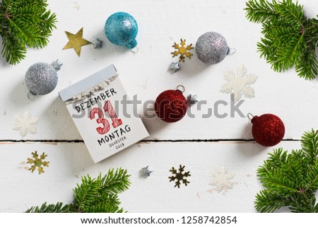 tear-off calendar with 31st of december 2018, silvester (in German) on top surrounded by christmas decoration on white background
