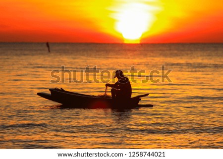 Silhouette of fisherman and sunrise on the sea