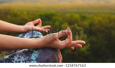 Young woman practicing yoga or pilates at sunset or sunrise in beautiful mountain location
