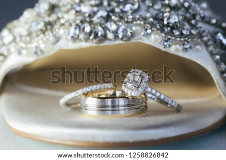 3 stacked wedding rings inside brides wedding shoe.  Royalty-Free Stock Photo #1258826842