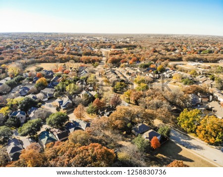 Aerial view residential neighborhood with sprawl subdivision in background. Flyover single-family houses with colorful autumn leaves in Flower Mound, Texas, USA, blue sky