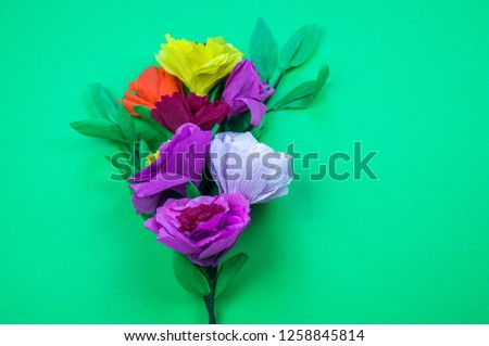 Utensils and tools for making crepe paper flowers on green background. Cosmos flower bouquet