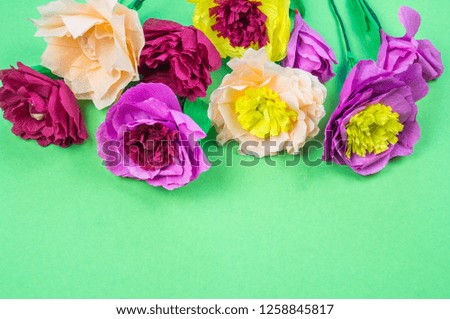 Utensils and tools for making crepe paper flowers on green background. Cosmos flower bouquet
