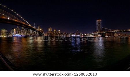 New York at night. Stitched panorama of a lower Manhattan from Empire Fulton Ferry park with Brooklyn and Manhattan bridges.  