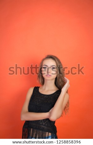 Fashionable young girl posing in the studio on a red background and looking at the camera