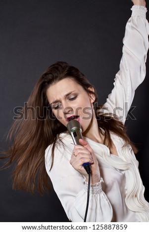girl singing into a microphone on a black background