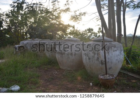 Old and antique big earthen jars, handmade, containing rainwater for household, arranged outdoor on the ground behind the house while the ray of the sun going to set shining through the area