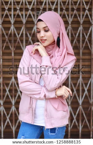 Half body portrait fashion shot of sweet and cute Asian girl wearing pink hijab.