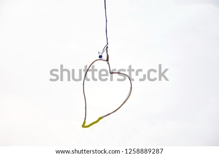 Heart shape hanging on white sky background, handicraft made from wood and wire in heart form iconic of love active for Valentine's day festival, white isolated with space for copy or text 