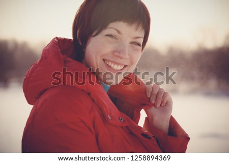 Beautiful young happy smiling woman brunette girl with short haircut in red jacket in winter park