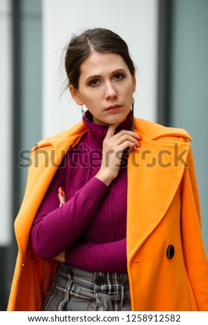 Elegant woman in a coat walks around the city in autumn