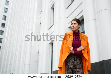 Elegant woman in a coat walks around the city in autumn
